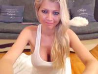 A busty blonde is getting naked while teasing