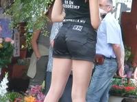 Frisky girl in cowboy hat and sexy shorts is teasingly waving ass cheeks in the street
