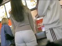 Sexy doll in white tight fitting jeans is waiting for her order in the fast food cafe