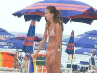 The pretty amateur gadget in the striped sexy bikini is playing active games on beach