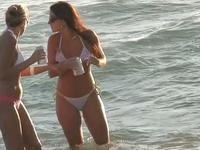 Charming bikini chicks are staying in the water talking and having no idea to be spied
